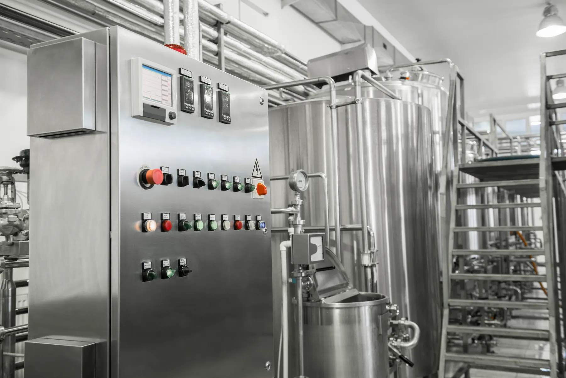 Dairy processing tank and control panel inside an industrial food facility
